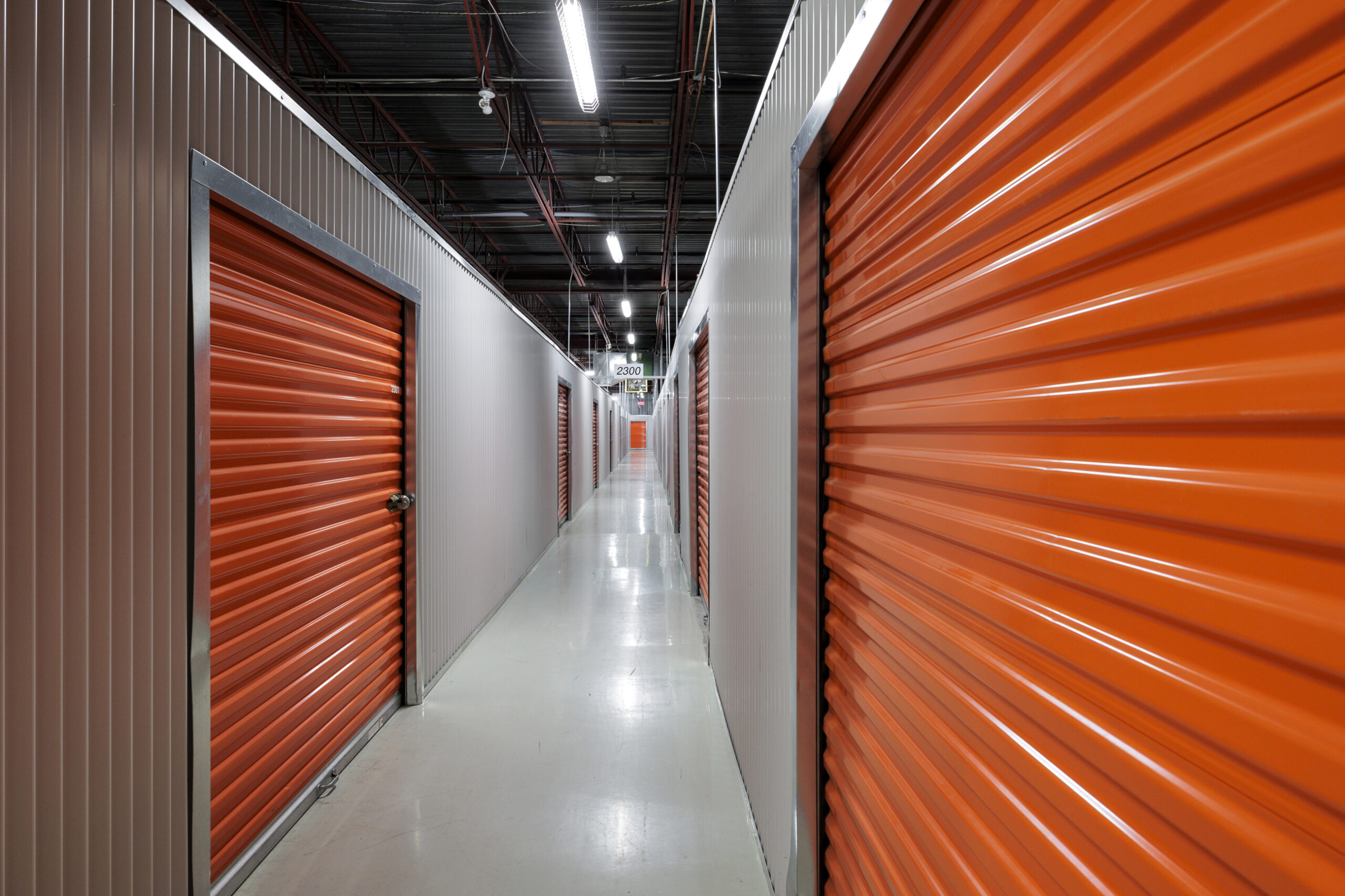 Un grand couloir facilite l’accès aux mini-entrepôts. Les portes des entrepôts sont oranges et le format est proportionnel à la grandeur de l’entrepôt. Plus l’entrepôt est grand, plus la porte sera grande pour faciliter l’accès.